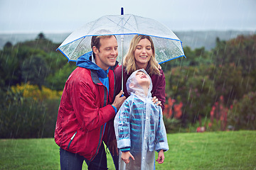 Image showing Family, happy and outdoor in rain with umbrella in nature for fun, happiness or quality time. Man, woman and excited child with cover for water drops with freedom, love and care while playing at park