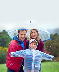 Image showing Portrait, family and happy portrait in rain with umbrella outdoor in nature for fun, happiness and quality time. Man, woman and excited child together for water drops, playing and freedom with mockup