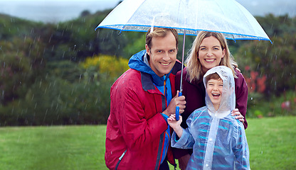 Image showing Family, happy and portrait in rain with umbrella in nature outdoor for fun, happiness and quality time. Man, woman and boy child with protection for water drops with freedom while playing in winter