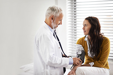 Image showing Blood pressure, doctor and a woman patient at hospital for a consultation with health insurance. Man with a stethoscope to check pulse of person for medical exam, wellness and hypertension diagnosis