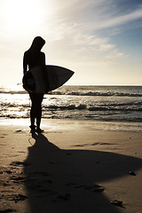 Image showing Silhouette, woman surfer on beach sand and ocean, exercise outdoor and healthy with surfboard and scenic sea view. Sports, shadow and sun with female person in nature and ready to surf for fitness