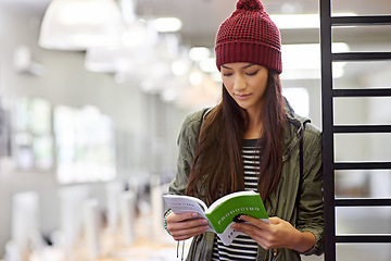 Image showing Woman with book, student in library reading and study for exam or research on university campus. Education, learning and academic development with female person holding textbook for knowledge