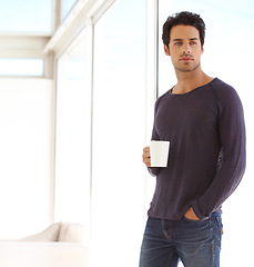 Image showing Handsome, casual and man with coffee standing by the window in a vacation house. Calm, relax and attractive male person drinking a mug of latte in the living room while thinking or having a dream.