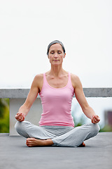 Image showing Senior woman, lotus pose and yoga on a floor outdoors for meditation, relax and zen, calm and healing. Mindfulness, meditating and mature female with breathing exercise for peace, wellness or balance