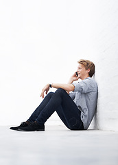 Image showing Man, phone call and floor with space by wall with smile, communication and talk at startup. Young businessman, entrepreneur and sitting for conversation on smartphone with mockup at small business