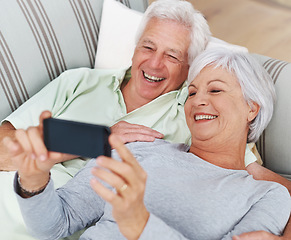 Image showing Senior, happy couple and relax for selfie on sofa in living room with smile for photo, memory or profile picture at home. Elderly man and woman smiling for photograph, vlog or social media on couch