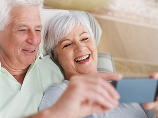 Image showing Happy senior couple, selfie and relax on sofa in living room with smile for photo, memory or profile picture at home. Elderly man and woman smiling for photograph, vlog or social media on couch