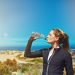 Image showing Woman drink water, health and fitness with blue sky, athlete outdoor with hydration and mockup space. Exercise at beach, female person drinking h2o from bottle with workout and break from training