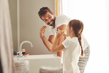 Image showing Dental care, father with daughter brush their teeth and in bathroom of their home. Oral hygiene routine, parent with child use toothbrush for health and wellness mouth protection in the morning