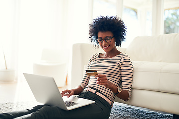 Image showing Young woman, laptop and credit card on living room rug doing online shopping sitting on ground. Home, happiness and computer with African female person on a ecommerce app reading information to buy