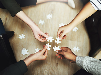 Image showing Hands, business people and puzzle in circle, huddle or teamwork for problem solving, solution or game in top view. Group, together and helping with support, synergy and team building on office floor