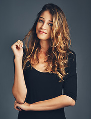 Image showing Beauty, portrait and a woman playing with hair in studio with a smile, makeup and cosmetics for skin glow. Aesthetic female model with salon results, shine and growth shampoo on a grey background