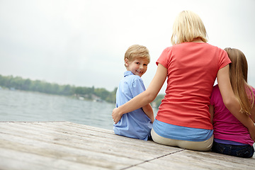 Image showing Woman, kids and back for portrait at lake during holiday with water in the outdoor with space. Family, child and mock up with river on the deck for vacation during summer to relax with freedom.