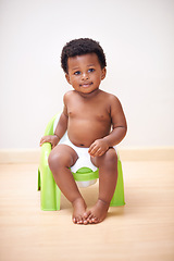 Image showing African baby boy, potty training or toilet in home with youth, learning and childhood development on floor. Young toddler, black child or kid sitting in bathroom with diaper, growth and plastic seat