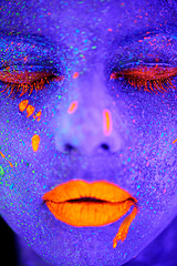 Image showing Neon paint, beauty and woman face closeup with dark background and creative cosmetics. Glow, rave makeup and psychedelic cosmetic of a female model with unique and creativity with art in studio