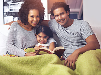 Image showing Child, reading book and family portrait in a home for story time on a lounge sofa with mom and dad. A woman, man and girl child together for development, learning and love with a fantasy or fairytale
