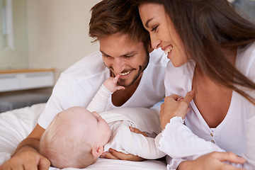 Image showing Happy father, mother and baby on bed for love, care and quality time together. Parents, newborn kid and relax in bedroom of family home with smile, childhood development and caring support of bonding