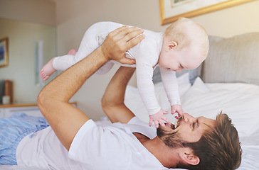 Image showing Father, on bed and play with baby girl up in the air or flying daughter and having fun in the bedroom feeling happy. Parent, kid and dad bonding or carefree and excited together in the house