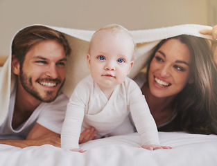 Image showing Mother, father and baby under blanket on bed for love, care and quality time together. Portrait of playful child, happy family and kids relaxing in bedroom with bedding fort, fun and bonding in house