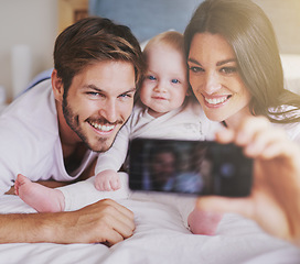 Image showing Happy family, parents and selfie of baby on bed in home for love, care and quality time together. Mother, father and newborn child smile for photograph, fun memory and happiness of bonding in bedroom