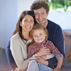 Image showing Family hug in portrait, relax in backyard with mom and dad with kid with love and care outside house. Faces of happy people with smile, woman and man with girl child together at home outdoor