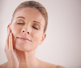 Image showing Face, beauty and mockup with a mature woman in studio on a mockup background for natural antiaging treatment. Facial, skincare and wellness with an attractive elderly female model touching her cheek