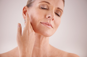 Image showing Face, beauty and skincare with an old woman in studio on a gray background for natural antiaging treatment. Facial, skin care and wellness with an attractive senior female model touching her cheek