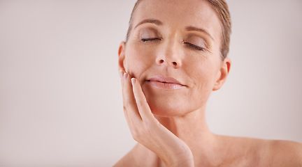 Image showing Face, beauty and mockup with a mature woman in studio on a gray background for natural antiaging treatment. Facial, skincare and wellness with an attractive senior female model touching her cheek