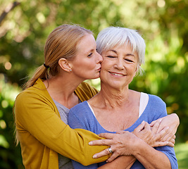 Image showing Adult daughter kiss mom, hug and trust with peace outdoor, family spending quality time in garden together. Women are content in relationship with love, bonding and solidarity in nature park