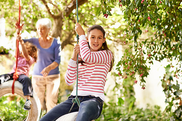 Image showing Young girl, garden and grandma playing with grandkid on background or holidays, having fun on a tyre swing in summer. Excited, grandchildren and outdoors on jungle gym or on sunny portrait at a park