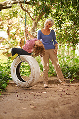 Image showing Elderly woman, garden and grandchild playing with grandma or holidays and having fun on a tyre swing in summer. Excited, grandkid and outdoors on jungle gym together or on sunny weekend at a park