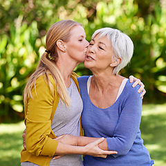 Image showing Adult daughter kiss mother, hug and trust with peace outdoor, family spending quality time in garden together. Women embrace while they relax in park, love and care with bonding and affection