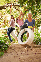 Image showing Grandmother, garden and grandkids playing with senior woman on tyre swing or holiday and having fun in summer. Excited, grandchildren and outdoors on jungle gym together or on sunny weekend at a park