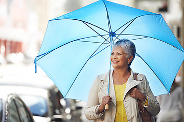 Image showing Walking, umbrella and senior happy woman on city commute, travel and smile on urban journey. Winter weather, happiness and female person looking at Mexico street view, commuting and walk on road