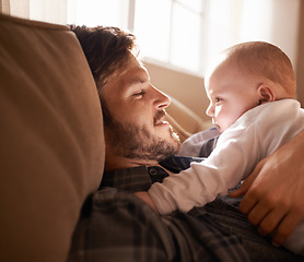 Image showing Smile, father and bonding with baby on sofa in home living room or playing together. Happiness, care and dad cuddle with infant, newborn or child on couch in lounge, having fun or enjoying relax time