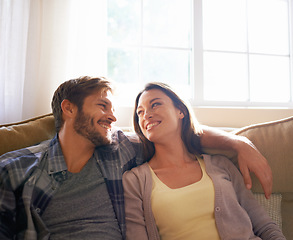 Image showing Couple, love and hug or smile at each other on a couch or in the living room and conversation. Man, woman and relationship or bonding and happy partners affectionate or at home relaxing and embrace