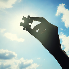 Image showing Hand, puzzle and solution with clouds in sky with problem solving, lens flare or bright ideas in sunshine. Silhouette, jigsaw and light for strategy, innovation or synergy for connection with person