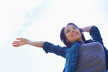 Image showing Happy, sky and arms with a woman outdoor in nature for fun, freedom or adventure in summer from below. Smile, financial freedom and wellness with a young female person outside for peace or dance