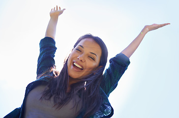 Image showing Portrait, celebrate life and arms with a woman outdoor in nature for fun, freedom or adventure in summer from below. Smile, clear sky and wellness with a happy young person outside during the day