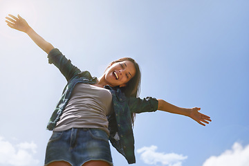 Image showing Portrait, blue sky and arms with a woman outdoor in nature for fun, freedom or adventure in summer from below. Smile, health and wellness with a happy young female person outside to celebrate life