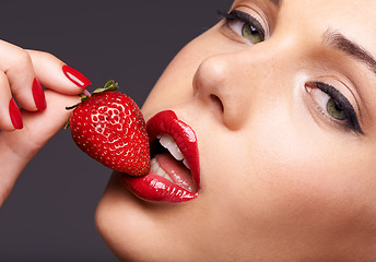 Image showing Beauty, portrait and model with a strawberry in studio with red nails and lipstick cosmetics. Health, wellness and closeup of woman with makeup eating fruit for nutrition isolated by gray background.