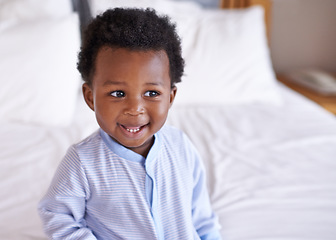 Image showing Happy, curious and baby laughing in bed, waking up and playing in his home. Face, smile and african boy toddler in a bedroom cheerful, having fun and sweet, cute and playful while relaxing alone