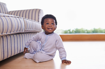 Image showing Black baby boy sitting on floor in living room, childhood development with growing happy kid at family home. African male toddler, cute child relax on wood floor with growth and learning mobility