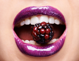 Image showing Closeup of woman lips with purple lipstick, makeup and beauty with shine and vibrant aesthetic, creativity and glow. Fruit between female model teeth, cosmetic product for mouth and cosmetology