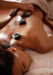 Image showing Hands, hot stone massage and woman in spa with luxury service for muscle, body and relax with peace in resort. Masseuse, hospitality and physical therapy on bed for wellness, zen and natural healing