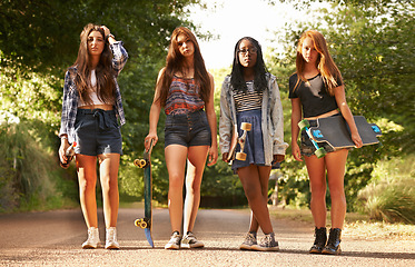 Image showing Girl friends, skateboard and portrait outdoor with diversity in summer on holiday in a road. Female student, sunshine and youth skateboarding of young gen z group and teen people on vacation