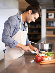 Image showing Cooking, man and smile in a kitchen with food, vegetables and ingredients for meal. Happy, male person and healthy diet in house for nutrition eating and chef learning with wellness from chopping