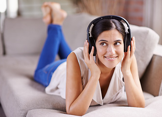 Image showing Happy woman, headphones and listening to music on sofa for thinking, comfort or relaxing at home. Female lying on living room couch with headset for audio sound track or relax on holiday break