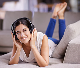 Image showing Happy woman, headphones and listening to music with smile on sofa for free time, comfort or relaxing at home. Female lying on living room couch with headset for audio sound track or relax on holiday