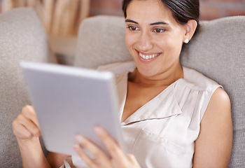 Image showing Happy woman, tablet and relax for online entertainment, streaming or social media on living room sofa at home. Female relaxing with smile using technology for app or research lying on lounge couch